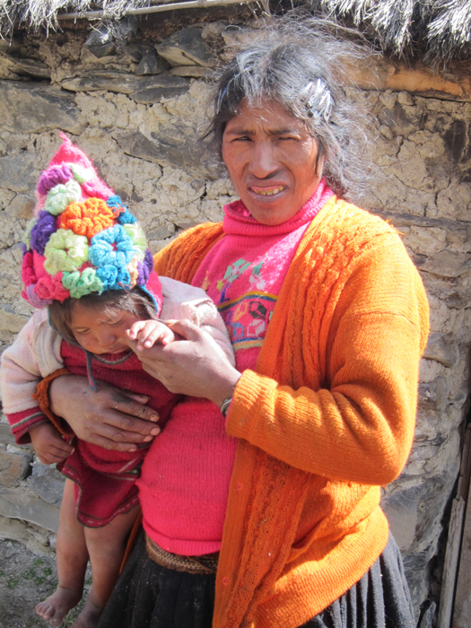 Local mother holding her child who will both benefit from a water spigot outside their home.